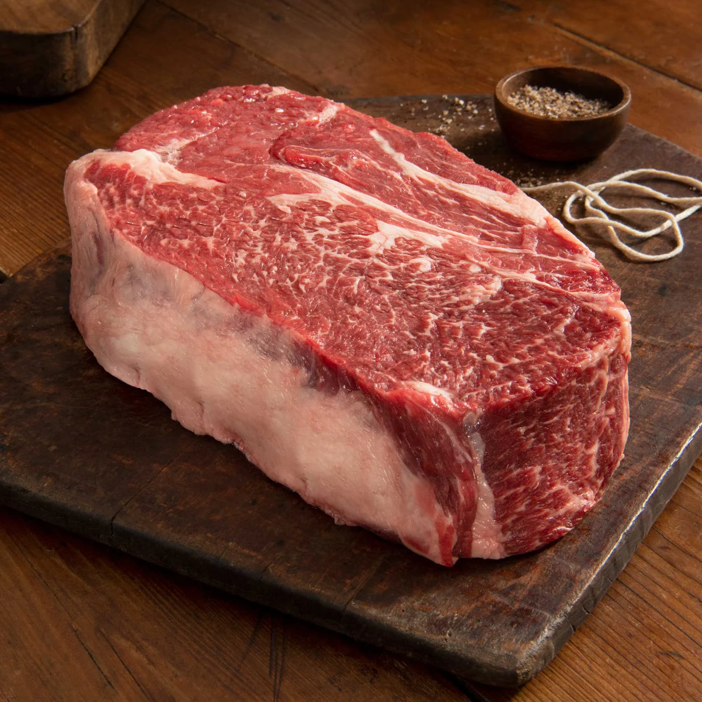 uncooked beef chuck roast on cutting board with cup of seasoning